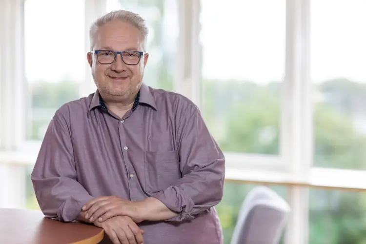 Jörg Schimke, SEO-Spezialist für KMU und freie Berufe, Portrait. Jörg schaut freundlich und lehnt an einem Stehtisch.